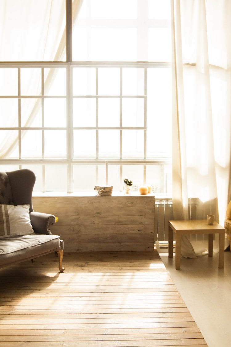 Bright sunlit room with armchair by large window representing calm and growth
